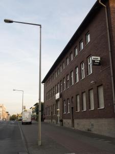 Ein weißer Van steht neben einem Backsteingebäude. in der Unterkunft Hotel Westend in Köln