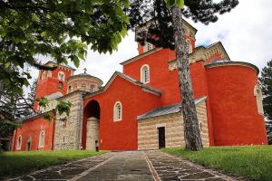 a red church with a tree in front of it at Boris Apartmani Kraljevo in Kraljevo