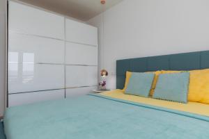 a bedroom with a large bed with yellow and blue pillows at Apartments Paloc - Yellow in Bol
