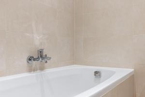 a white bath tub with a faucet in a bathroom at Trendy apt with - smart TV, coffee machine in Meidling in Vienna