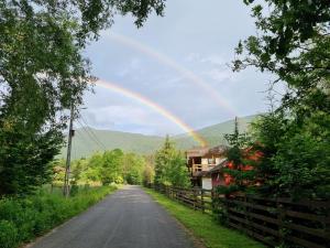 a rainbow in the sky over a road at Casa Alin Poiana Mărului in Poiana Mărului