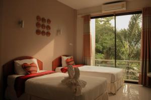 una camera da letto con due letti e una finestra con balcone di Thai Lao Resort and Spa โรงแรมไทลาว รีสอร์ท แอนด์ สปา a Nakhon Phanom