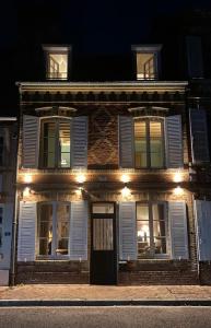 une vieille maison en brique éclairée la nuit dans l'établissement Maison de charme Beaumont, proche Deauville, à Beaumont-en-Auge