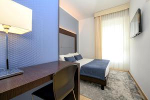 1 dormitorio con 1 cama y escritorio con TV en Hotel City, en Desenzano del Garda