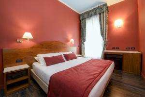 a bedroom with a bed with red walls and a window at Hotel City in Desenzano del Garda