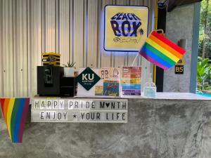 una mesa con una cometa arco iris y un feliz signo de mes de orgullo en BeachBox@Koh Сhang, en Ko Chang
