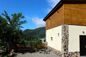 a white building with a wooden roof and a tree at Likani-house's Cottage in Borjomi