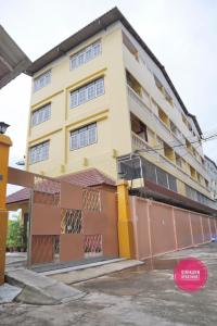 een geel gebouw met balkons in een straat bij Sirikarn Apartment in Bangkok