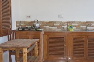 a kitchen with wooden cabinets and a table and a stove at Milhams Guesthouse in Bwejuu