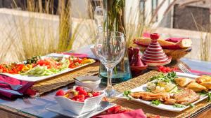 a table with plates of food and a glass of wine at Riad Jardin Des Sens & Spa in Marrakesh