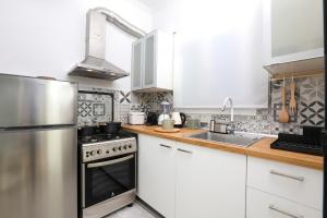 a kitchen with white cabinets and a stainless steel refrigerator at Terranova beach apartments - Jasmine in Ýpsos