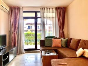 a living room with a couch and a large window at Lovely 1BD Apartment in a Luxury Resort in Sozopol in Sozopol