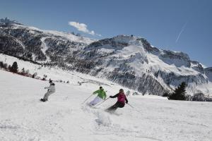 three people skiing down a snow covered mountain at B&B Villa Ursula in Moena