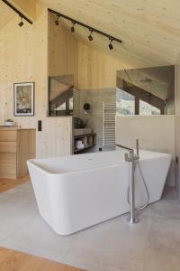 baño con bañera blanca grande y paredes de madera. en Chalets Santner, en Sankt Jakob in Defereggen