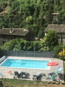 uma piscina com cadeiras e um guarda-sol em Le grenier de l Aigoual em Valleraugue