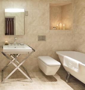 a bathroom with a sink and a toilet and a bath tub at The Boleyn Hotel in Staines