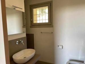 łazienka z umywalką, toaletą i oknem w obiekcie Cascina Pianetta Quinta w mieście Missaglia