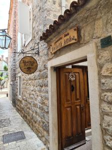 a stone building with a door and a sign on it at Beatrix Suites in Budva