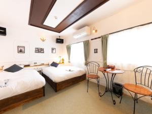 a hotel room with two beds and a desk at Tabist Hotel Nizi Fuefuki Misaka in Fuefuki