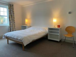a bedroom with a bed and two tables and a chair at Luxury 2-bedroom apartment near beach in St Andrews in St. Andrews