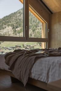 a bed in a room with a large window at Chalets Santner in Sankt Jakob in Defereggen