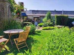 Le Relais Des Dalles في Sassetot-le-Mauconduit: طاولة وكراسي في حديقة مع منزل