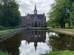 un edificio antiguo con un reflejo en un estanque en Kasteel Ryckevelde en Sijsele