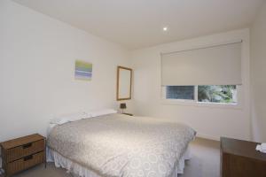 a white bedroom with a bed and a window at Beachside At Breakers in Lorne