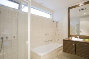 un bagno con vasca, doccia e lavandino di Beachside At Breakers a Lorne