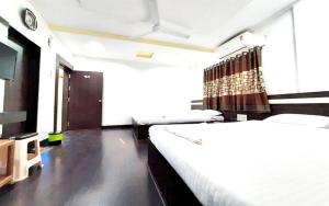 a bedroom with two beds and a flat screen tv at Hotel United House in Shirdi