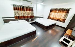 a bedroom with two beds and a curtain at Hotel United House in Shirdi