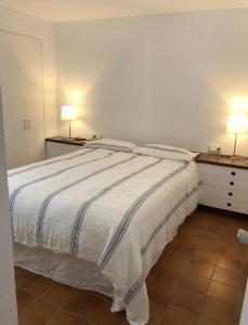 a bedroom with a bed and two lamps on two tables at CENTRIC APARTMENT CADAQUES -private parking - CA L'ELLA in Cadaqués