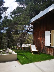 a chair sitting in the grass next to a building at Un chalet au Ventoux - Mont Serein in Mont Serein