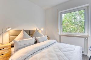 a white bedroom with a large bed with a window at Haus Kleemann E24 in Norderney