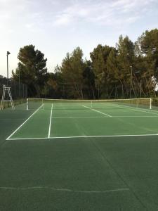 una pista de tenis verde con una red en Château la Sable, chambres d'hôtes en Cucuron