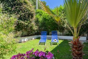 two blue chairs sitting in a yard with flowers at Casette all'Addaura by DomuSicily in Mondello