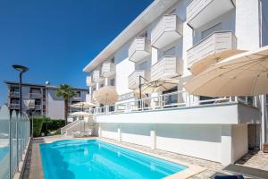 un edificio de apartamentos con piscina y sombrilla en Hotel Villa d'Este en Grado