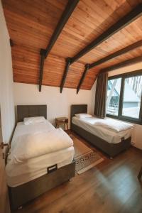two beds in a room with wooden ceilings at Meselik Park Bungalov in Sapanca +21 photos