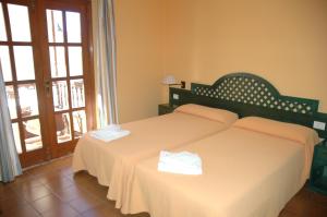 a bedroom with two beds with white sheets and a window at Hotel Jardín Concha in Valle Gran Rey