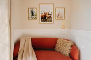 - un canapé orange dans une pièce avec trois photos sur le mur dans l'établissement Villa Rafa, à Costa Nova