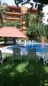 une piscine avec des chaises et un parasol et un bâtiment dans l'établissement Hotel Puerta Del Mar Ixtapa, à Ixtapa