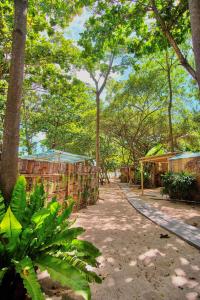 a path in a forest with trees and buildings at Beach House Camp in Na Jomtien