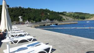 a row of white lounge chairs next to the water at Apartment LAGUNA 64 in Izola