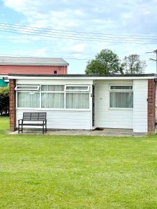 a white house with a bench in front of it at Sundowner Chalet Great For Families in Great Yarmouth