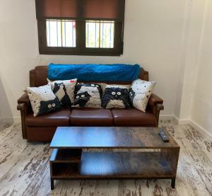 a brown leather couch with pillows and a coffee table at La Casita in Ventas de Zafarraya