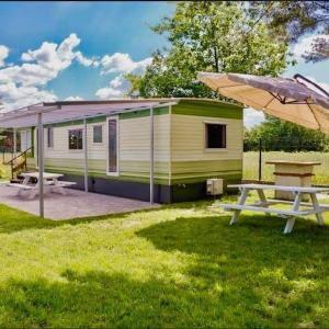 a green and white caravan with a picnic table and an umbrella at Uroczysko Warta in Uniejow