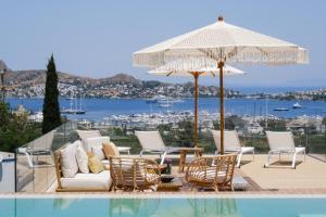 a patio with a table and chairs and an umbrella at Birdcage 33 Hotel - Adult Only in Yalıkavak