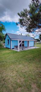 une maison bleue dans un champ avec un arbre dans l'établissement Uroczysko Warta, à Uniejów
