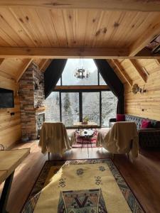 an attic room with a table and chairs and a large window at Riona dağ evleri in Çamlıhemşin
