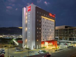 een hotelgebouw met veel auto's geparkeerd op een parkeerplaats bij Ibis Queretaro in Querétaro